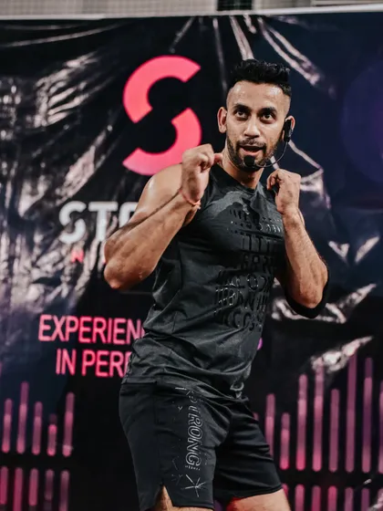 A focused moment during a Strong Nation masterclass. This high-intensity workout is all about precision and power, with every punch, squat, and burpee synced perfectly to the music. As a Master Trainer, I guide you to perfect your form and find your inner strength.