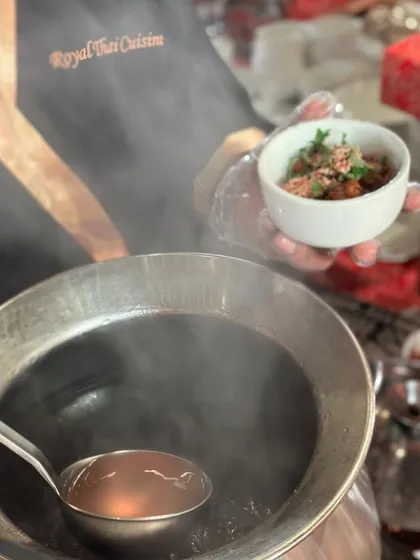 A chef pours steaming hot broth for a Thai noodle soup. The use of traditional pots and ladles adds to the authenticity of our live stations.