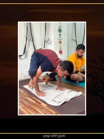 A student practices the initial stages of Kaakasana (Crow Pose), learning to balance with support from a towel for better grip.