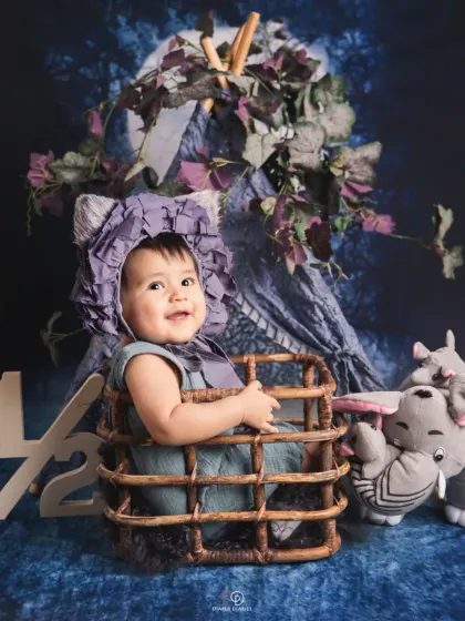 Celebrating the half-birthday milestone at six months old. This happy baby sits in a wicker basket with a '1/2' sign, showing off a huge, infectious giggle.