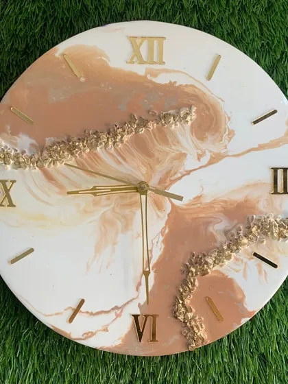 A warm and inviting clock with a beige and white marble design, accented with gold crystals.