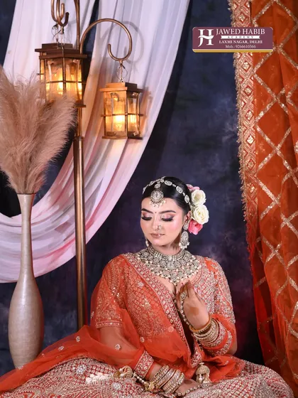 A full view of a bride seated in a decorated setting. We teach our students how to create looks that complement the grandeur of Indian weddings.