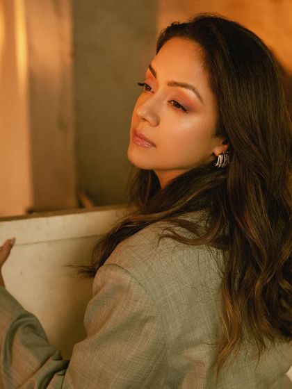 A close-up on Jyotika's profile, showing the sunset-hued makeup that complements the neutral tone of the suit.