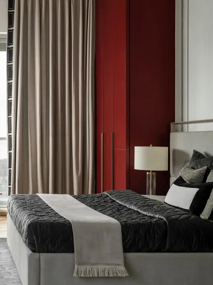 The deep maroon wardrobe in this master bedroom provides a bold pop of color. The clean lines and brass handles add a touch of modern luxury, complementing the room's sophisticated palette.