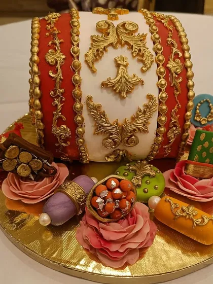 A festive and intricate cake designed to look like a traditional dhol drum. This cake is perfect for weddings, sangeets, or cultural celebrations, adorned with detailed gold patterns and edible decorations.