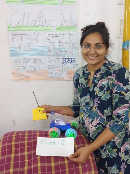 Success. A participant proudly shows off a remote control car that she fixed during our workshop. The smile on her face is the reason we do what we do.