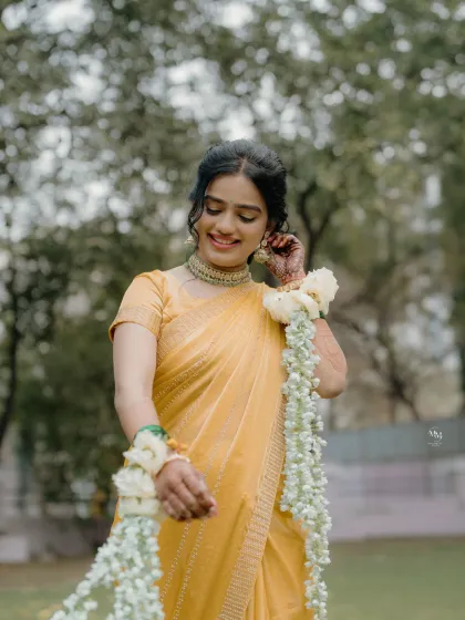 A beautiful portrait of the bride in her yellow Haldi saree, adorned with delicate floral jewelry. Her shy smile captures the essence of a bride-to-be.