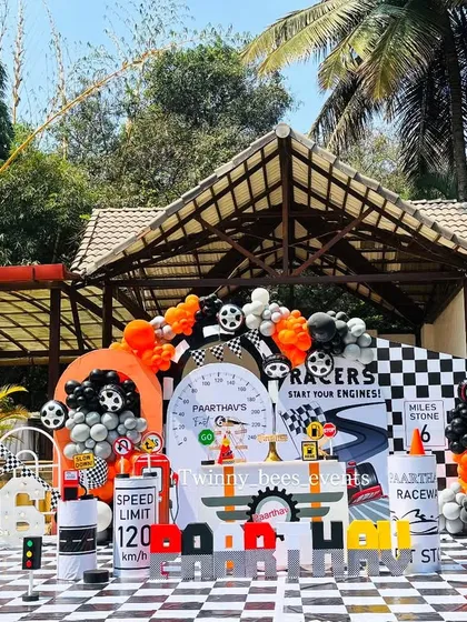 This is how we do a first birthday. We created a full-scale outdoor car racing theme, complete with a chequered floor, custom racetrack backdrop, and themed props like traffic cones and fuel barrels for Paarthav's big day.