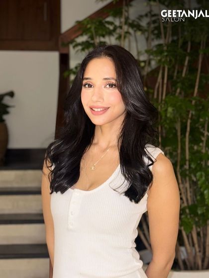 A classic black hair colour that looks striking and timeless, styled with soft, bouncy waves.