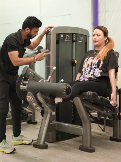 My approach to personal training is hands-on. Here, I am guiding a client through a leg extension, ensuring her form is perfect to maximize results and prevent injury.