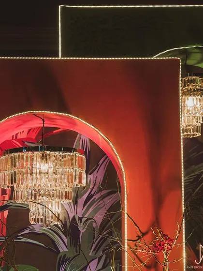 Detail of the layered stage backdrop, showing how crystal chandeliers emerge from within the arched, tropical-print panels to add a touch of unexpected glamour.
