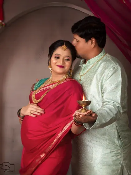 A tender kiss on the forehead and the warm glow of a diya (lamp) create a deeply emotional and spiritual portrait for this expecting couple.