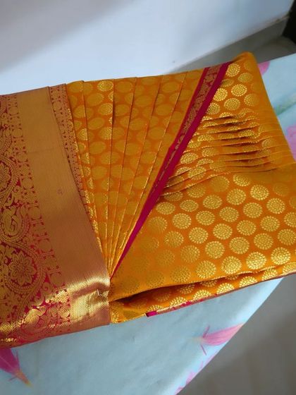 A perfectly pre-pleated and box-folded yellow silk saree. This is the result of my professional service, ready to be delivered.
