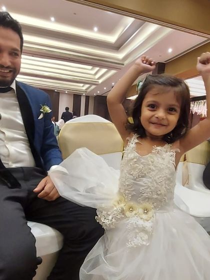 A candid moment of happiness at a wedding reception. This little girl is wearing a custom white tulle dress with delicate floral applique, designed for both beauty and comfort.
