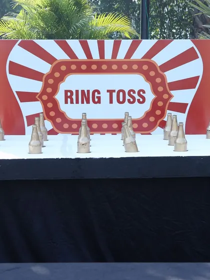 The classic ring toss game, set up with glass bottles and a professionally designed backdrop. It's a game of skill that always draws a crowd at carnival-themed events.