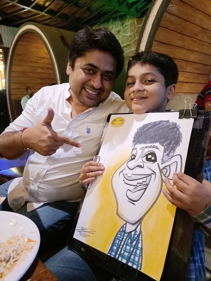 A father and son duo, both pointing at the fun caricature.