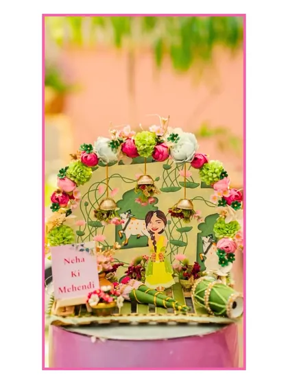 A close-up of the intricate, custom-made table centerpiece for the Mehendi, featuring a miniature bride and dhol.