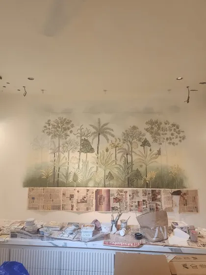 The mural in progress. This behind-the-scenes shot shows the dining area protected by newspaper as the artwork takes shape, revealing the messy but beautiful process of creation.