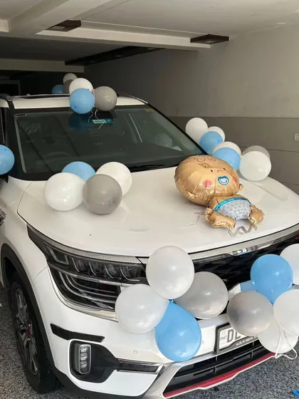 A simple car decoration to bring the newborn baby boy home in style. The car hood is adorned with blue, grey, and white balloons and a baby-shaped foil balloon.