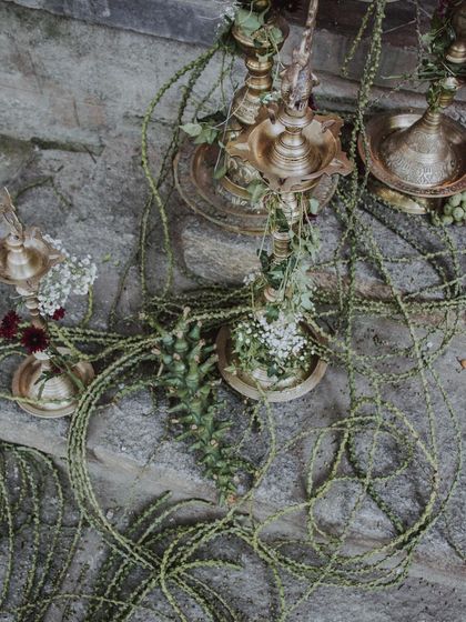 A detail of the organic floral decor from the 'Love in Ruins' wedding, with vines and flowers wrapped around traditional brass lamps.