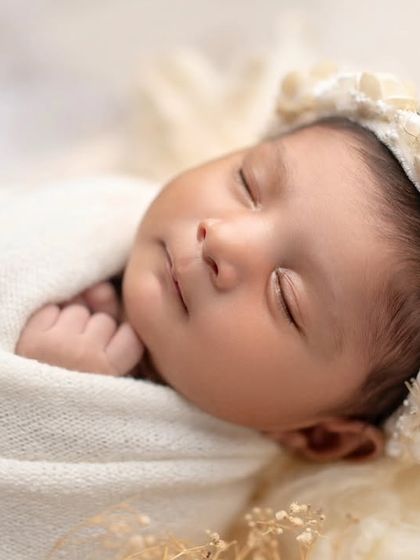 A close-up of a perfectly swaddled newborn, adorned with a beautiful floral headband. Pure and simple elegance.
