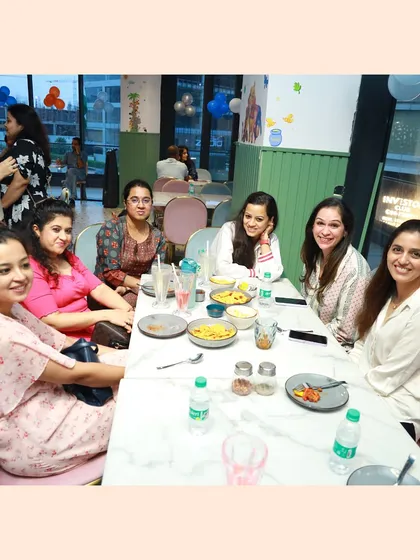 It's not just about the kids. We've created a space where parents can connect and unwind. Here, a group of moms enjoys a meal together, sharing laughs while their children play safely nearby.