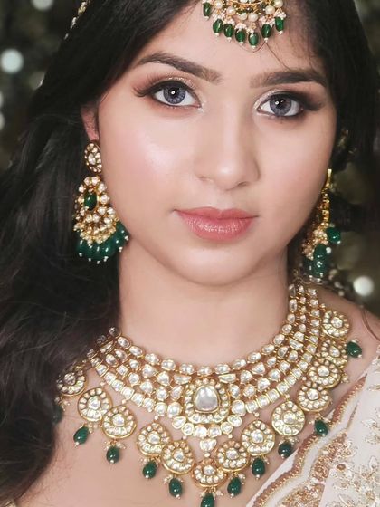 A classic and elegant look featuring a multi-layered Kundan necklace with green bead drops, paired with a white and gold outfit.