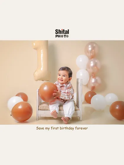 A happy one-year-old playing with balloons. The simple, neutral-toned setup keeps the focus on the baby's joyful expression.