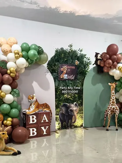 I create immersive jungle theme parties with life-sized animal props like tigers, deer, and giraffes. This setup features custom green and brown balloon arches, a grass wall backdrop, and themed "BABY" blocks, perfect for a wild first birthday or a baby shower.