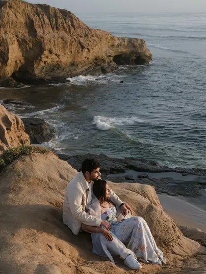 Overlooking the vast ocean from a rocky cliffside. This dramatic, scenic shot is perfect for adventurous couples who want their pre-wedding photos to have a sense of scale and wonder.