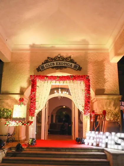 A classic reception entrance at Club Exotica. We combined a red carpet walkway with a beautiful red floral draped archway and personalized marquee letters for the couple's hashtag, #MAISHA.