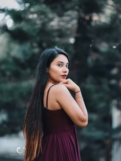 A classic over-the-shoulder glance. Her expression is confident and alluring, and the natural setting provides a beautiful backdrop.