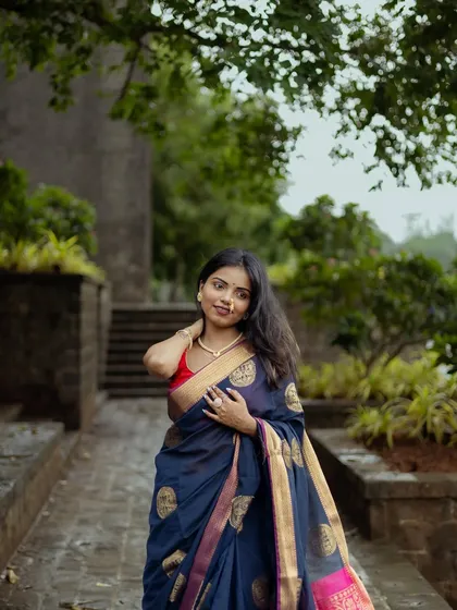 A lovely portrait taken on a pathway surrounded by trees. The model's pose is natural and elegant, showcasing the saree in a relaxed, outdoor setting.