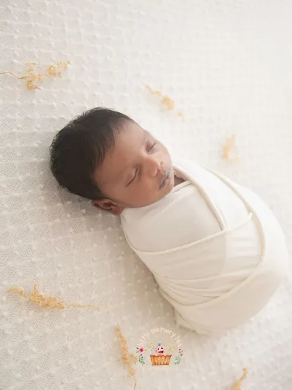 A full-body shot of a baby in a classic swaddle. This pose is all about simplicity and showing how tiny and curled up your newborn is in their first few weeks.