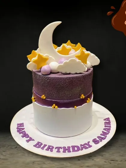 A beautiful and serene cake featuring a crescent moon and golden stars nestled in fluffy white clouds. The purple and white design creates a dreamy night sky effect.