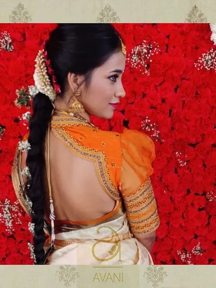 A unique blouse design with sheer puffed sleeves and a detailed cutout back. The orange organza fabric adds a light, airy feel, while the embroidery keeps it rooted in tradition.