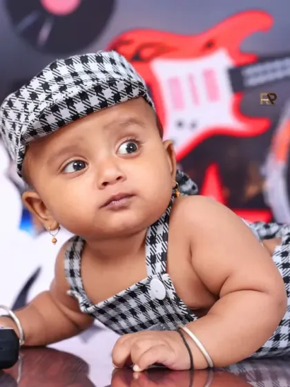 A close-up of the baby boy in the music-themed shoot, looking off to the side with a curious expression. The details of the set, like the toy keyboard, add to the playful vibe.