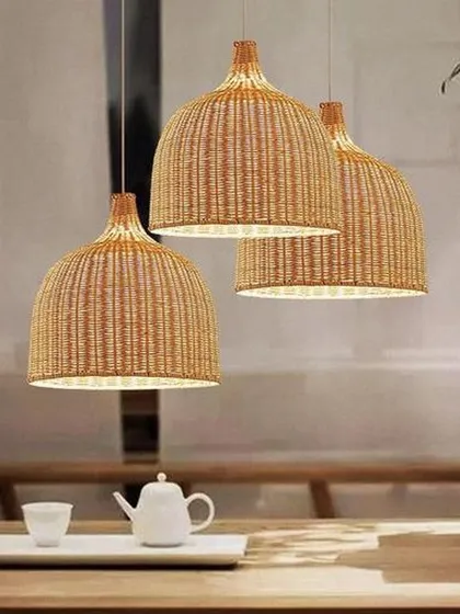 A set of three bell-shaped, woven rattan pendant lights hanging over a dining table. This classic design is perfect for creating a focused yet warm light source, ideal for kitchens, dining areas, or cafes.