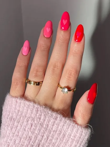 A closer view of the romantic pink and red gradient manicure with heart details. The glossy finish makes the colors pop, creating a vibrant and polished look.