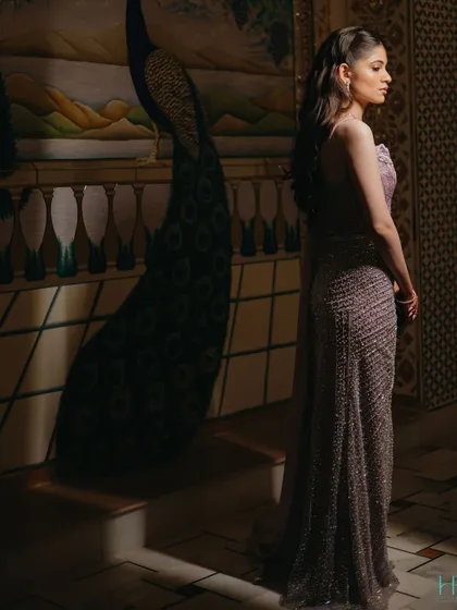 An elegant bridal portrait, with the bride looking away from the camera, showcasing the silhouette of her gown against a beautifully painted wall.
