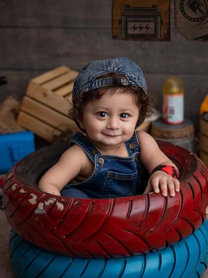 Such a charming smile from our little mechanic. This portrait shows him sitting happily amongst the tires and tools, looking right at the camera. These are the expressions you'll want to remember forever.