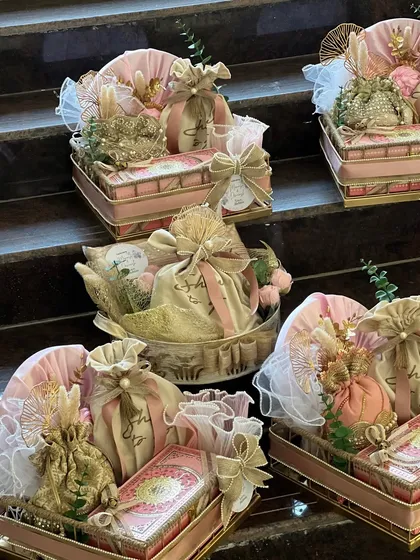 A collection of beautiful wedding invitation hampers, designed in a delicate pink and gold theme. Each hamper is thoughtfully arranged in ornate trays, ready to be sent to loved ones.