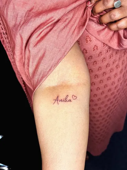 The name 'Aniha' with a small heart, inked in a delicate script. It's a sweet and personal piece.