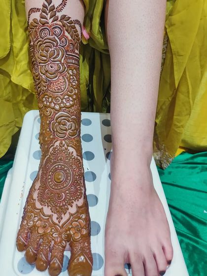 The process of creating a bridal foot design, showing one leg complete and the other ready for its art.