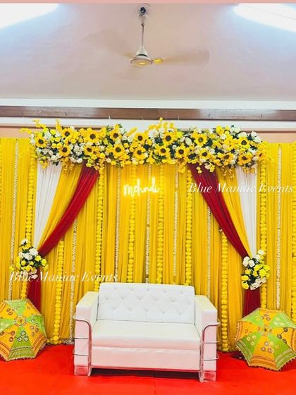 A wider view of the yellow Haldi/Mehendi setup, showing how it fits into a larger room. The white sofa and traditional umbrellas provide perfect seating and photo opportunities.