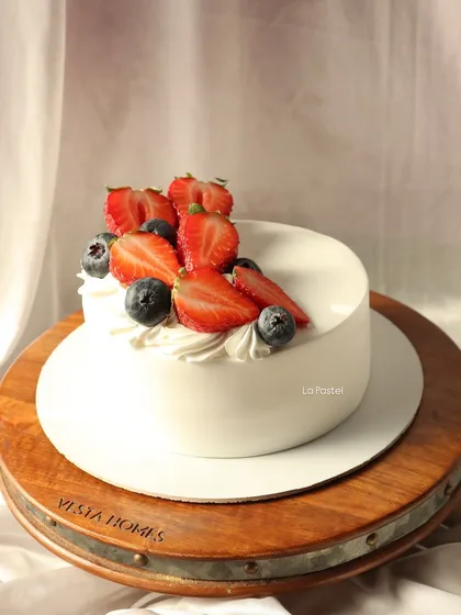 A simple, elegant, and delicious fresh berry cake on a rustic wooden stand.