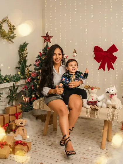 A mother and her child share a happy moment during their Christmas photoshoot. The festive background and their bright smiles perfectly capture the spirit of the season.