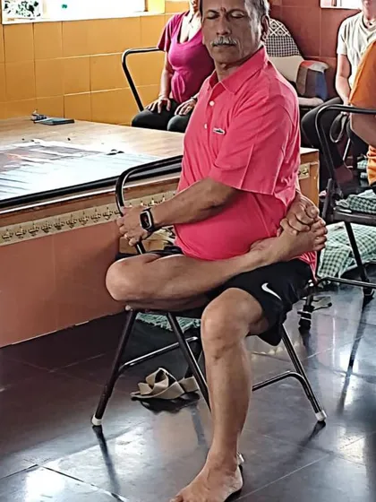 A seated hip-opening pose on a chair.