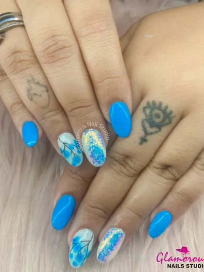 A vibrant blue set that combines solid color with accent nails featuring a delicate floral pattern and a touch of iridescent glitter.