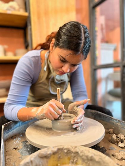 The intense focus of a creator at work. Trimming a piece on the wheel requires a steady hand and a calm mind, making it a deeply mindful practice.